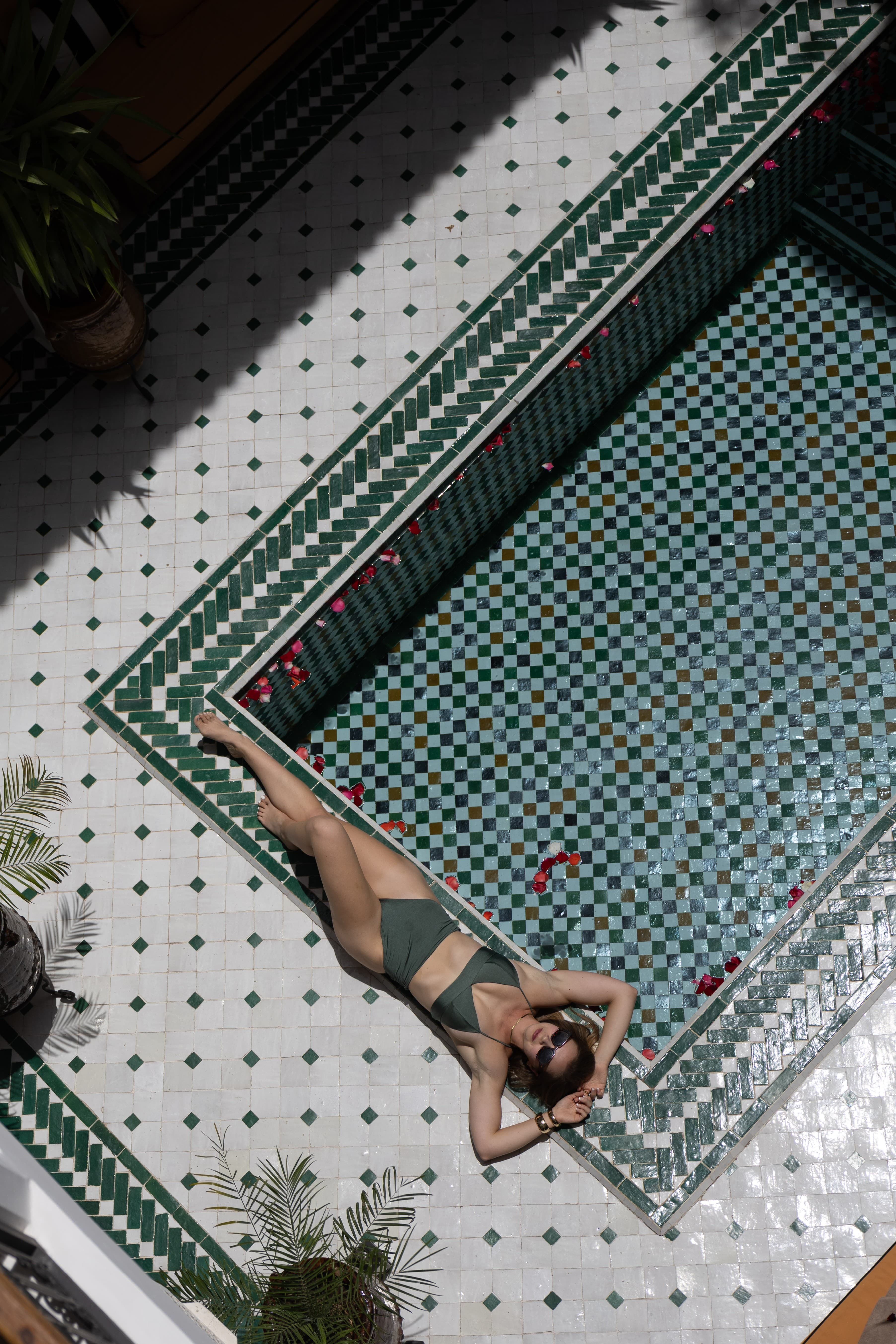 Woman lying beside a Moroccan tiled pool